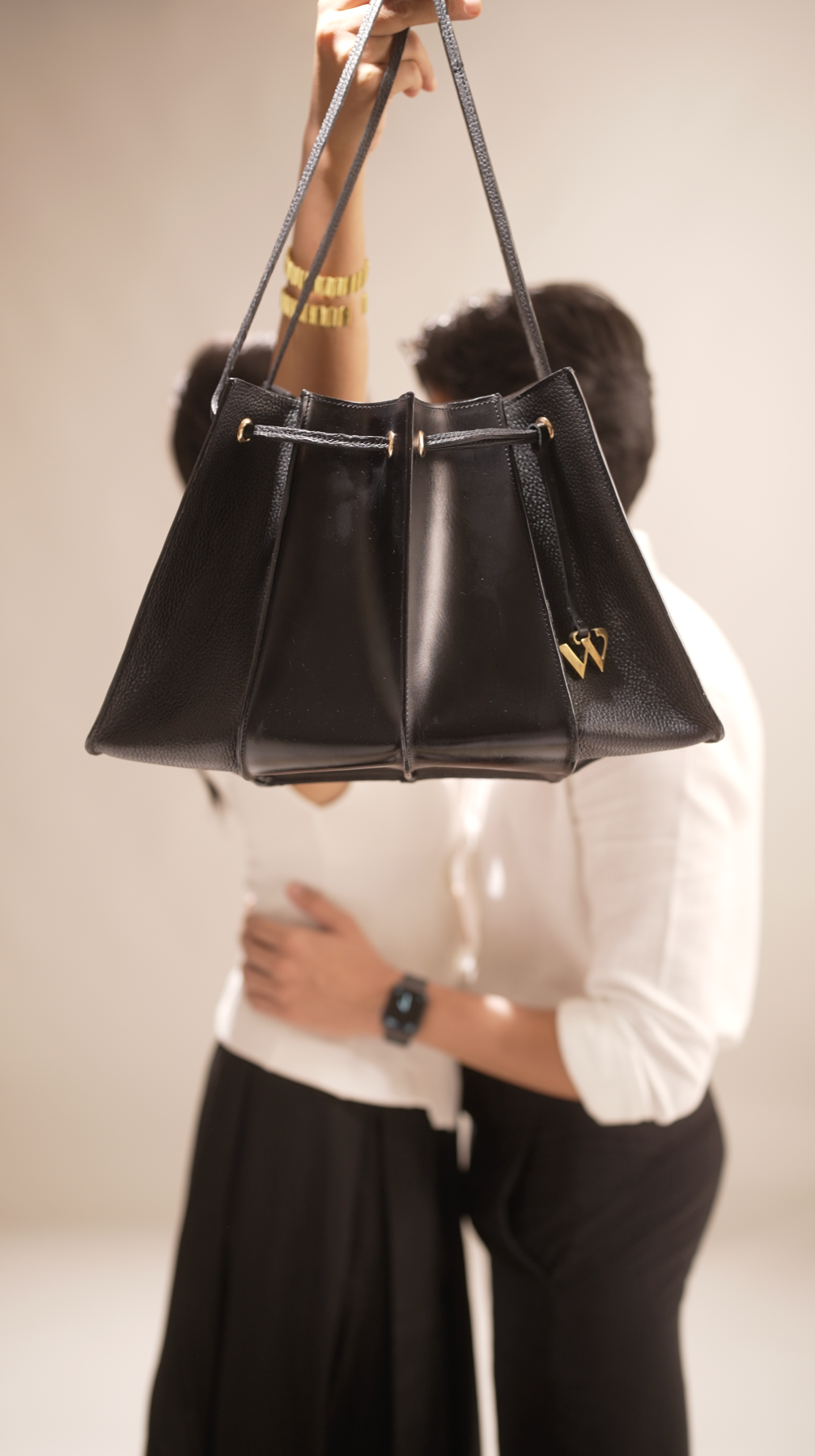 Person holding a black handbag with fur accents against a white background