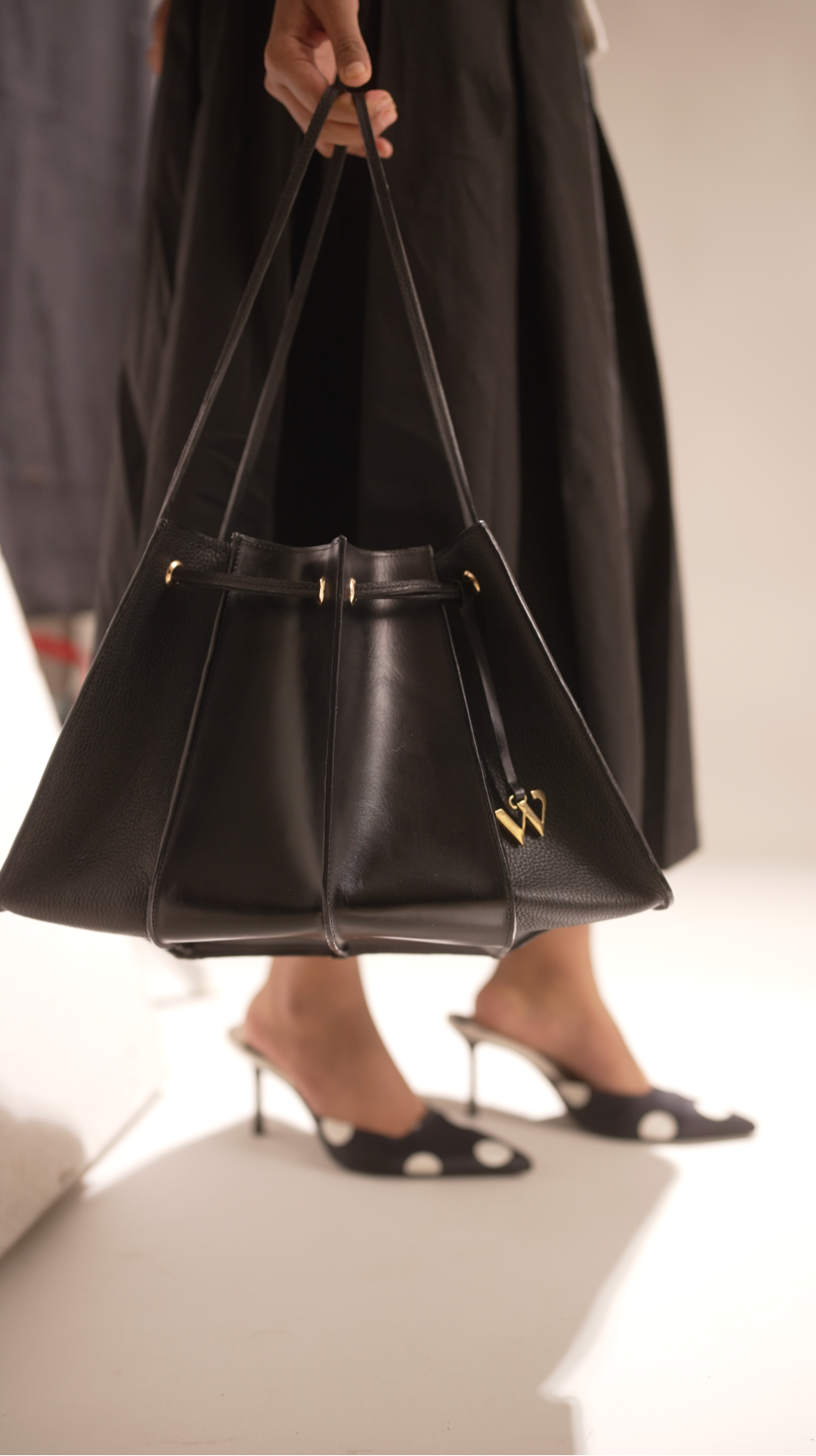 Person holding a black handbag on a plain background